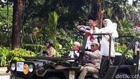 Menaiki jeep, Khofifah dan Emil tak henti melambaikan tangan dan menyapa para warga yang ikut serta dalam arak-arakan tersebut.
