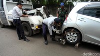 Petugas mengikatkan ban mobil untuk diderek.