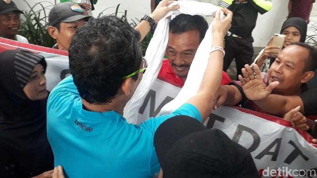 Sandiaga mengalungkan serban putih ke warga Bojonegoro yang membawa poster dukungan untuk Jokowi.