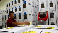 Pekerja menempelkan stiker bertuliskan arahan untuk memasukan surat suara Pemilu ke dalam kotak suara tersebut.