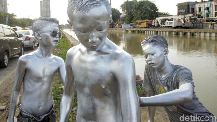 Sejumlah remaja yang mengecat seluruh tubuhnya dengan warna silver mengais rezeki dengan menghibur pengendara di kawasan Kalimalang, Bekasi. Begini aksinya.