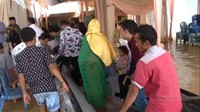 Keluarga pengantin menyediakan perahu karet untuk membawa tamu melewati banjir hingga ke pelaminan.