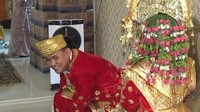 Mempelai lelaki, Ari tampak tersenyum. Prosesi pernikahan mereka berjalan lancar meski di tengah banjir.