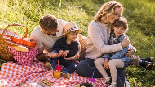 Happy parents enjoying with their kids during spring day on picnic.