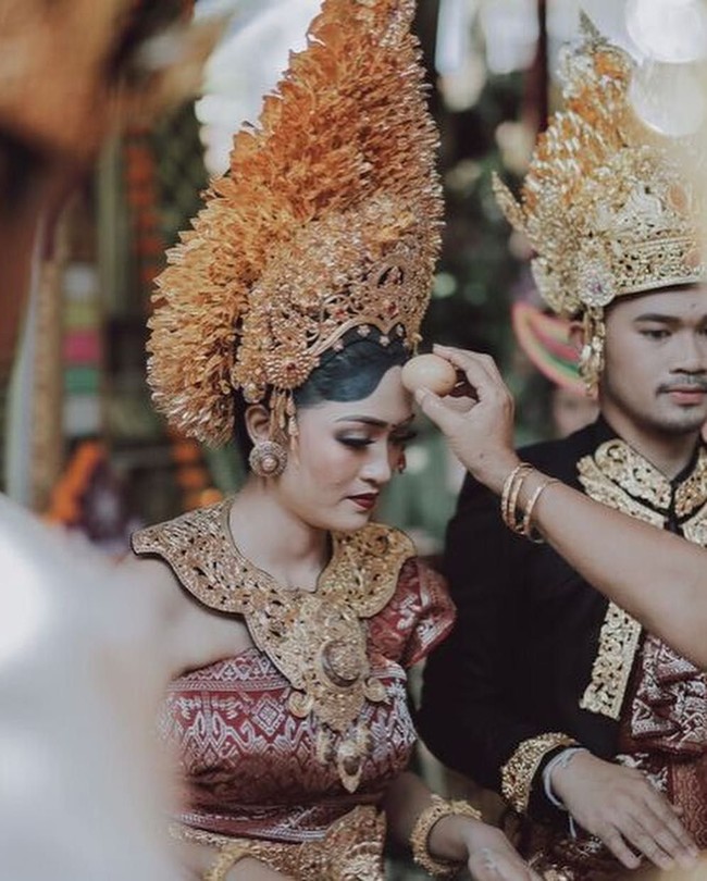 Prosesi adat pernikahan Berlin dan Anastasia berlangsung dengan sakral dan khidmat. Dalam upacara pernikahan tersebut tampak kedua mempelai memakai busana pengantin Payas Agung Badung. Kekhasan dari pakaian adat pengantin Bali yang berasal dari keluarga kerajaan atau bangsawan adalah mahkota emas berukuran besar yang juga dihiasi bunga sandat. Foto: Instagram @Allseasonsphoto, Instagram @rivieraeventorganizer
