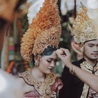 Prosesi adat pernikahan Berlin dan Anastasia berlangsung dengan sakral dan khidmat. Dalam upacara pernikahan tersebut tampak kedua mempelai memakai busana pengantin Payas Agung Badung. Kekhasan dari pakaian adat pengantin Bali yang berasal dari keluarga kerajaan atau bangsawan adalah mahkota emas berukuran besar yang juga dihiasi bunga sandat. Foto: Instagram @Allseasonsphoto, Instagram @rivieraeventorganizer