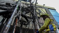 Petugas memangkas kabel semrawut yang mengganggu pemandangan.