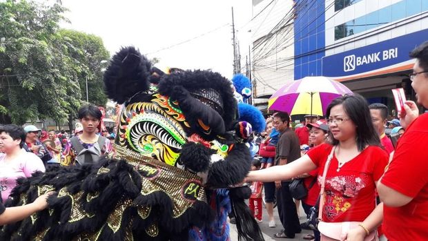 Warga memberikan angpao ke mulut barongsai.