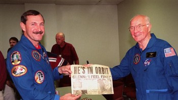 John Glenn di tahun 1998, memegang halaman depan surat kabar yang memampang pencapaiannya mengorbit Bumi. (Foto: Hulton Archive/Getty Images)