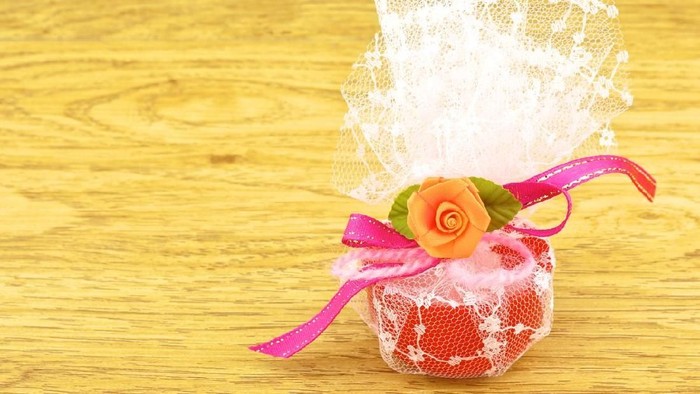 Camphor aroma in red cup wrapped in white mesh place on right with wood background.