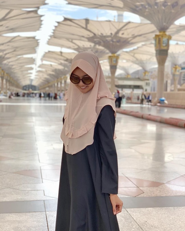 Kevin tampil sederhana saat beribadah umrah. Ia mengenakan khimar instan dan gamis berwarna netral. Saat ibadah umrah, kita dianjurkan untuk memakai busana yang tidak terlalu mencolok. Foto: Instagram/kevinlln