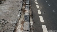 Disalah satu sisi dipinggir jalur trotoar nampakjuga jalan yang rusak dan bolong.