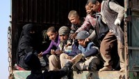 Salah satu tentara dari Pasukan Demokratik Suriah memberikan roti kepada anak-anak yang akan dievakuasi dari Desa Baghouz. Rodi Said/Reuters.