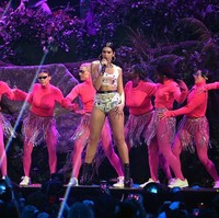 Dua Lipa lalu berganti pakaian. Kali ini mini dress biru bermotif bintang dengan aksen pita besar di belakang menjadi pilihannya. Untuk melengkapi gayanya, Dua mengandalkan anting berbentuk bintang. Foto: Getty Images