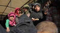 Anak-anak berkumpul memakan roti di tengah perjalanan menuju kamp pengungsian setelah meninggalkan tempat tinggal mereka di Desa Baghouz, yang berada dekat perbatasan Irak dan Suriah. Rodi Said/Reuters.