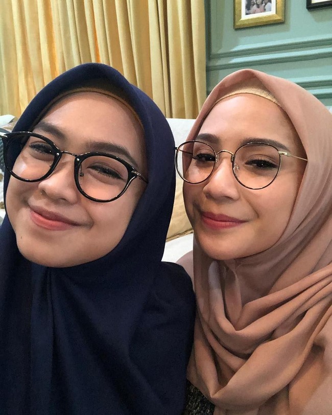 Nagita Slavina juga pernah tampil berhijab saat foto selfie dengan Ria Ricis. Gigi memakai hijab segi empat warna nude, dilengkapi dengan inner rajut warna senada. Sedangkan Ria Ricis memakai hijab segi empat warna biru dongker. Keduanya kompak mengenakan kacamata. Foto: Instagram/RiaRicis.