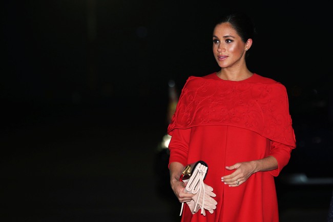 Berbalut gaun merah pendek nan anggun dari Valentino, Meghan menebar pesonanya. Clutch bewarna nude dari label yang sama turut melengkapi gaya perempuan 37 tahun itu. (Foto: Getty Images)