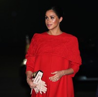 Berbalut gaun merah pendek nan anggun dari Valentino, Meghan menebar pesonanya. Clutch bewarna nude dari label yang sama turut melengkapi gaya perempuan 37 tahun itu. (Foto: Getty Images)