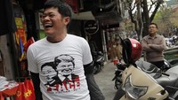 Seorang warga membeli baju bergambar Kim Jong Un dan Trump dengan tulisan Peace jelang pertemuan kedua pemimpin tersebut di kota Hanoi, Vietnam. Vincent Yu/AP Photo.