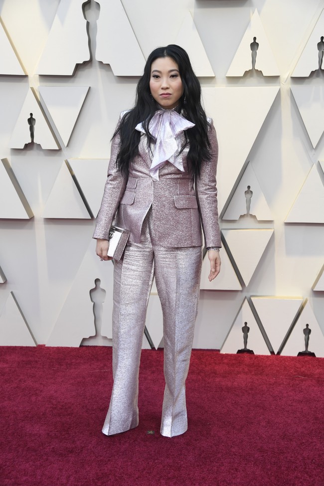 Tampilan maskulin menjadi pilihan Awkwafina. Tubuhnya dibungkus setelan metalik berkilauan dari DSquared2 yang dilengkapi dasi bergaya pussy bow bervolume. Foto: Getty Images