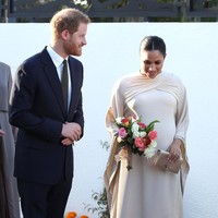 Meghan juga terlihat menenteng tas clutch satin yang juga didapatnya dari Dior. Padanan ini disempurnakan sepatu hak tinggi yang berwarna metalik. Foto: Getty Images