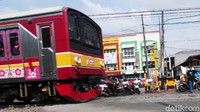 Penjaga pelintasan mengarahkan pengendara untuk tidak menerbos palang pintu.