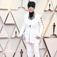 Diane Warren tampil dengan setelan putih berhias sequin yang mencuri atensi, namun hadir dengan potongan yang tak terlalu baik. Belum lagi aksesorinya berupa penutup leher dan kalung rantai membuat look ini layak masuk daftar busana terburuk. Foto: Frazer Harrison/Getty Images
