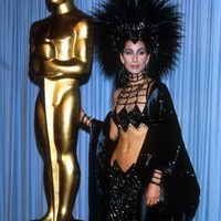Penyanyi eksentrik Cher tampil dengan gaun hitam dengn headpiece bulu besar menyerupai Maleficent di Oscar 1986. Foto: Dok. Getty Images