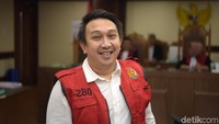 Ia pun hanya tersenyum karena sidang ditunda hingga minggu depan. Pool/Noel/detikFoto.