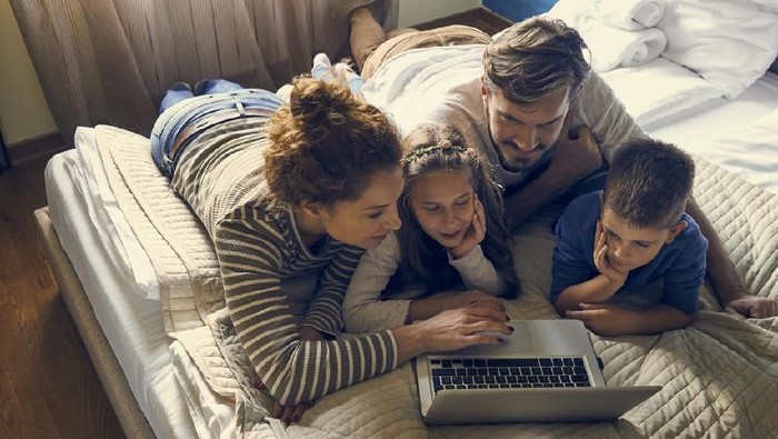 menonton film family having fun at home and using laptop together