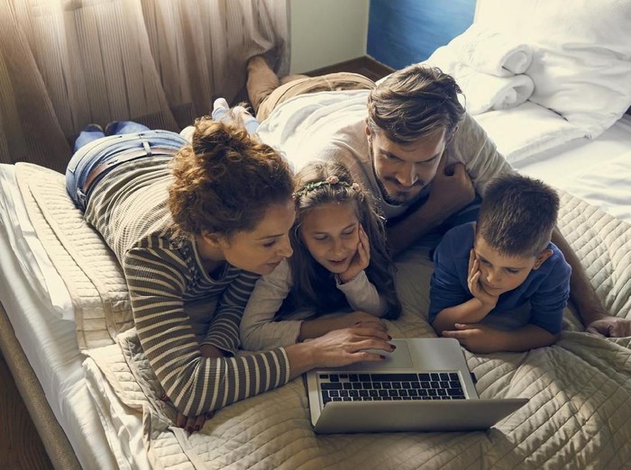 family having fun at home and using laptop together
