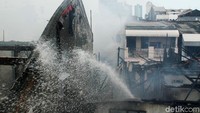 Meski telah padam, petugas masih menyiramkan air ke rumah warga yang terbakar agar titik api tidak menyebar akibat angin.