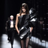 Look berikutnya menampilkan Kaia berbalut mini-dress metalik dengan aksen pita bervolume yang menutupi dada dan lengan kirinya. Rambut coklat alami Kaia kini dibiarkan tergerai bebas sehingga memancarkan kecantikan alami model 17 tahun itu. (Foto: Pascal Le Segretain/Getty Images)