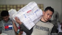 Relawan mengangkut plastik berisi beberapa gepok kertas suara. Kertas suara itu akan dikumpulkan menjadi satu dengan kertas suara lainnya sebelum dididistribukan.