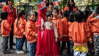Ada pula anak-anak yang tampil cantik dalam balutan pakaian tradisional Korea Utara saat akan menyambut Kim Jong di sekolah yang didirikan sejak tahun 1978 itu. Carl Court/Getty Images.