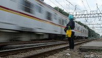 Warga menunggu kereta melintas.