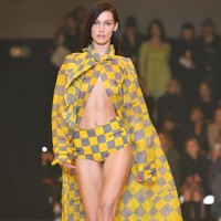 Sementara itu, sang adik muncul dalam balutan outerwear bermotif kotak kuning-abu yang menjuntai panjang. Busana tersebut hanya dipadukan dengan celana pendek senada sehingga mengekspos perut ratanya. (Foto: Pascal Le Segretain/Getty Images)