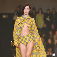 Kekasih The Weeknd ini muncul dalam balutan outerwear bermotif kotak kuning-abu yang menjuntai panjang. Busana tersebut hanya dipadukan dengan celana pendek senada sehingga mengekspos perut ratanya. (Foto: Getty Images)