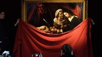 Para petugas Colnaghi Gallery melepaskan kain merah penutup lukisan untuk memperlihatkannya kepada publik. Leon Neal/Getty Images.