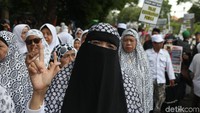 Massa mengenakan baju putih-putih. Massa membawa sejumlah bendera dan spanduk.
