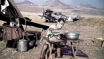 Seorang pilot Nazi menyempatkan diri bercukur di samping pesawat Messerschmitt Bf 109 di sebuah lokasi di Italia pada tahun 1943. Jerman berperang dengan sekutu kala itu antara lain di Sicilia. Foto: Luftwaffe in Colour