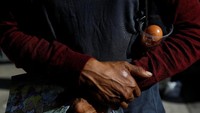 Seorang warga membawa pulang satu butir telur yang nampak telah retak dari tempat sampah di ibu kota Venezuela, Caracas.