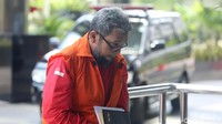 Eks anggota Sumut yang sempat buron tersebut terlihat menutupi tangannya yang terborgol dengan buku catatatan bersampul hitam. 