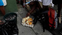 Seorang warga mengumpulkan sisa roti yang didapatkannya dari tempat sampah.