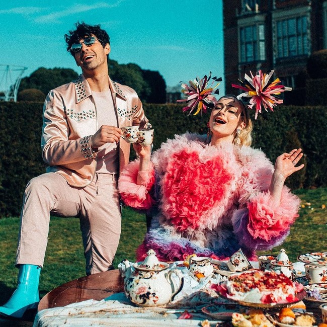 Sophie Turner tampil mencuri atensi dengan gaun ruffle dari Tomo Koizumi dan headpiece pom pom dramatis.  Foto: Dok. YouTube/The Jonas Brother