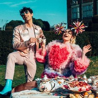 Sophie Turner tampil mencuri atensi dengan gaun ruffle dari Tomo Koizumi dan headpiece pom pom dramatis.  Foto: Dok. YouTube/The Jonas Brother