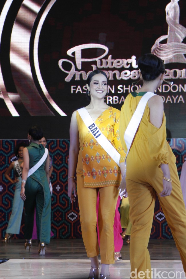 Finalis Puteri Indonesia 2019 dari Bali, Nadia Karina memakai jumpsuit kuning cerah yang tampak cantik di kulitnya. Sentuhan kain Indonesia tampak unik dengan aksen luaran di satu sisi. Foto: Mohammad Abduh/Wolipop