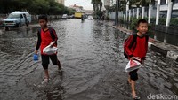 Sejumlah anak sekolah yang melintas menggulung celana dan memasukkan sepatu mereka ke dalam plastik agar tidak basah saat akan digunakan.