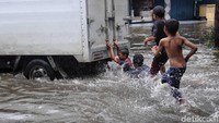 Meski berbahaya, anak-anak ini tetap bermain di genangan banjir sepulang sekolah.