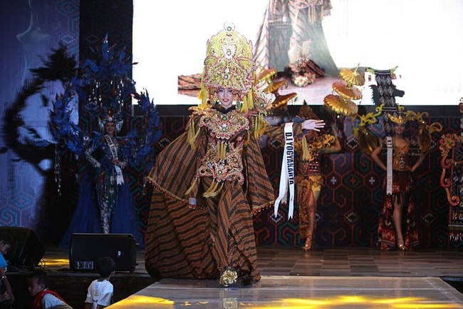 Keindahan kain lurik menjadi tema kostum yang menemani penampilan Anja Litani Ariella dari D.I. Yogyakarta. Gayanya kian sempurna dengan headpiece bernuansa keemasan yang dihiasi ukiran dramatis.  Foto: Instagram/@officialputeriindonesia